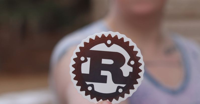 Brand Advocacy Programs - Close-up of Man Holding a Cutout with the Logo of Rust Programming Language